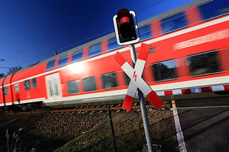 Regionalzug fährt über einen beschrankten Bahnübergang